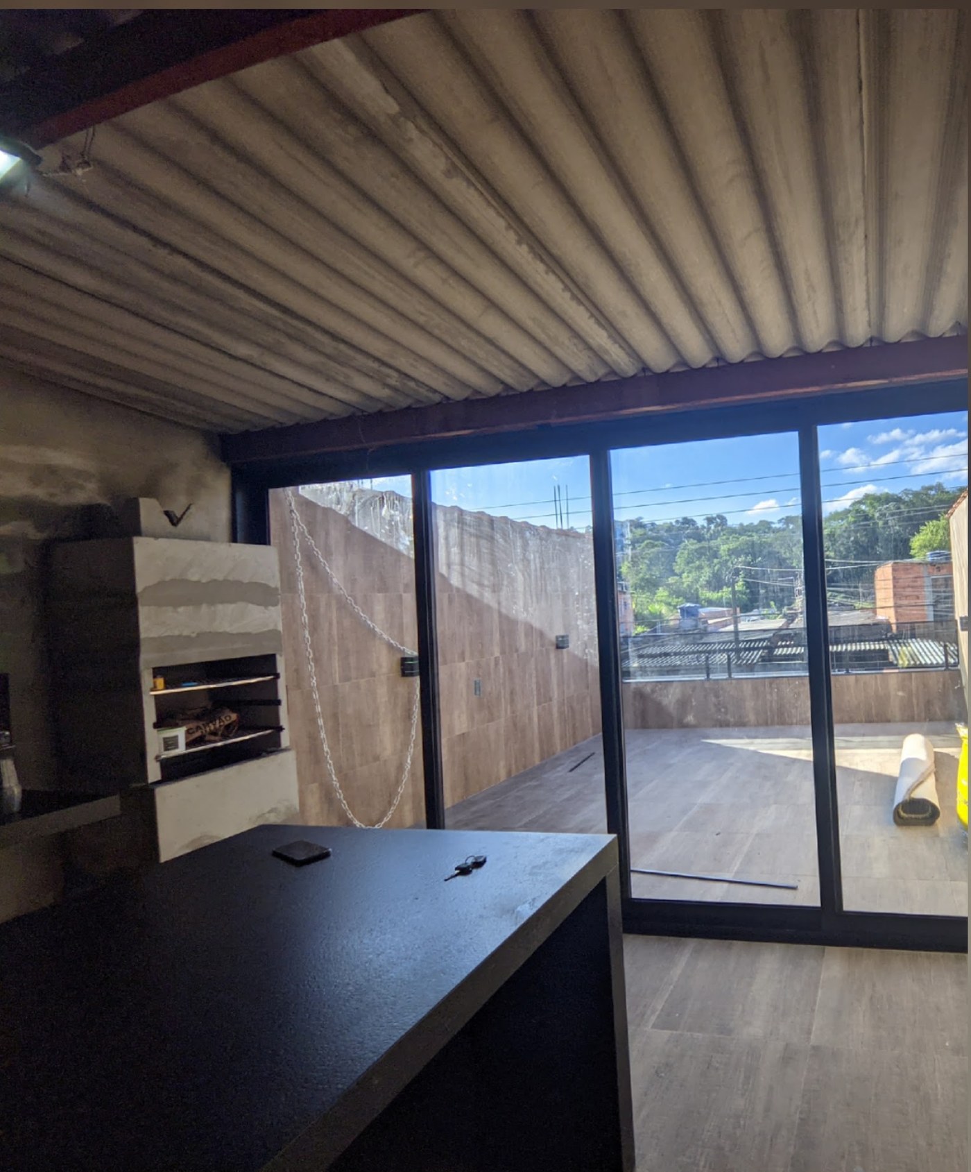 Ambiente interno com porta de vidro de correr de quatro folhas aberta para o terraço